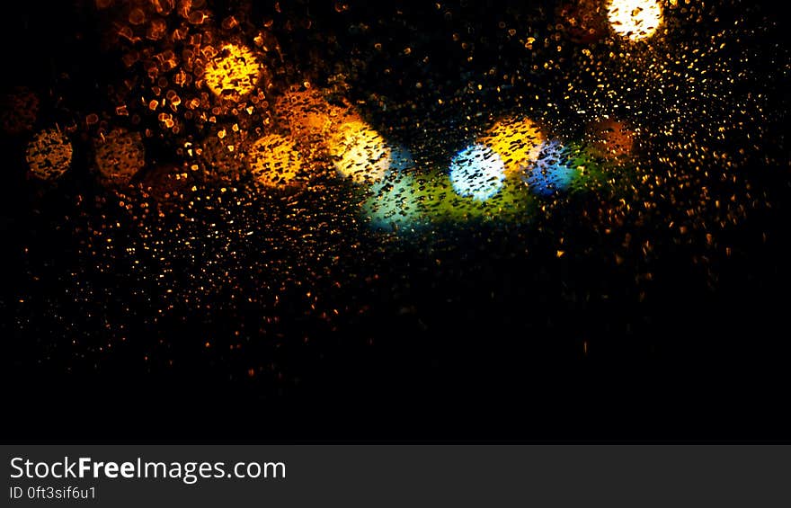 Colorful bokeh lights behind window with raindrops. Colorful bokeh lights behind window with raindrops.