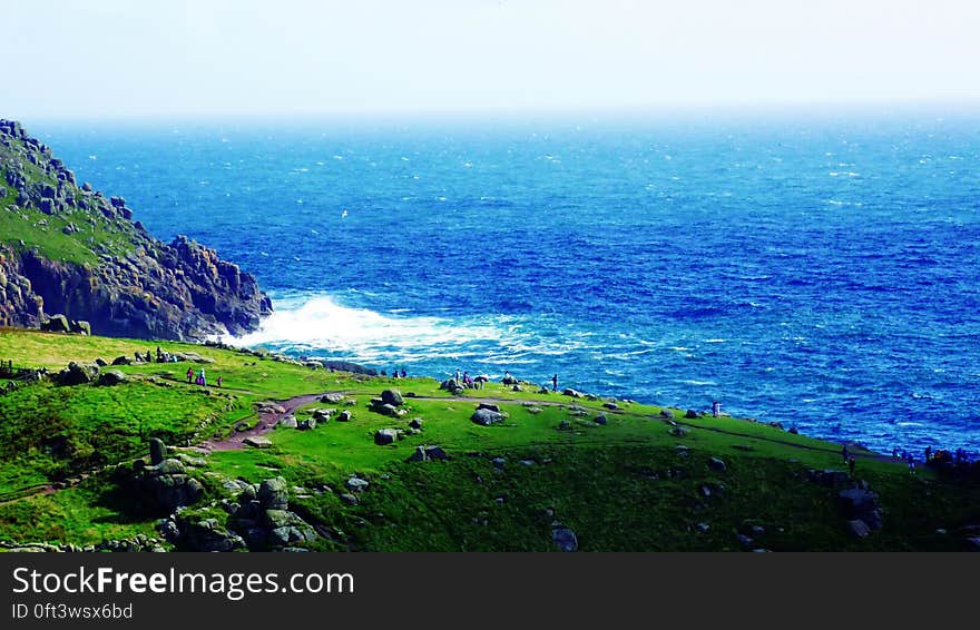 A view of a sea coast with green meadows and rock cliffs.