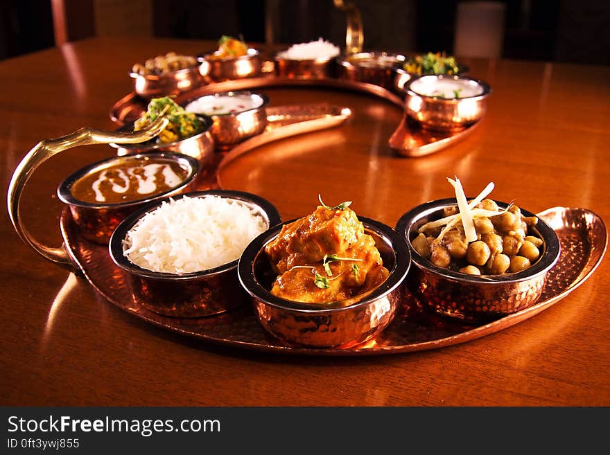 Copper tray with bowl of Indian dishes on wooden tabletop. Copper tray with bowl of Indian dishes on wooden tabletop.