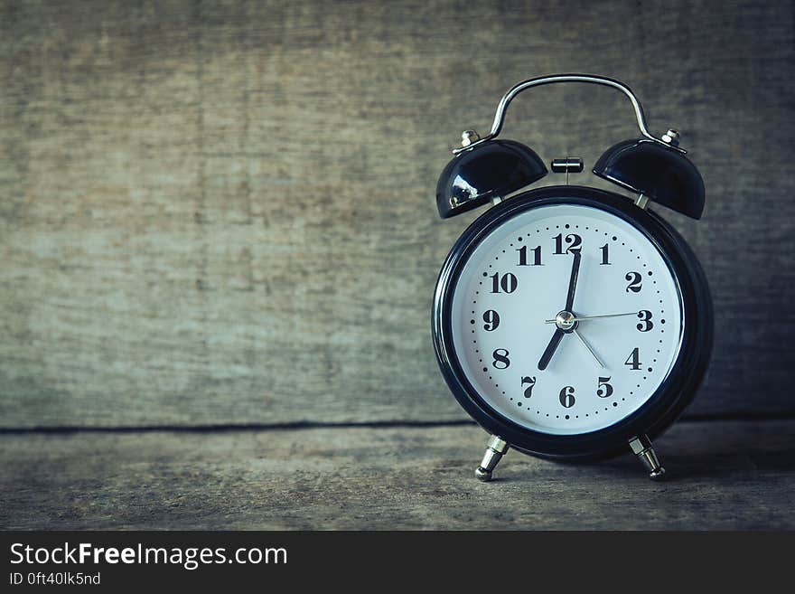 Old fashioned alarm clock on rustic wooden boards.