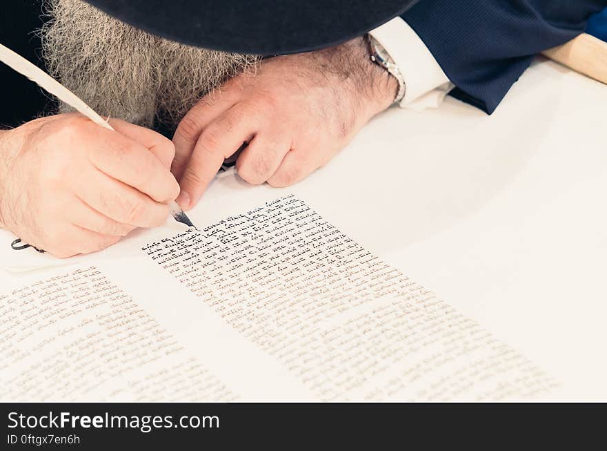 A bearded man writing with ink and a quill pen. A bearded man writing with ink and a quill pen.