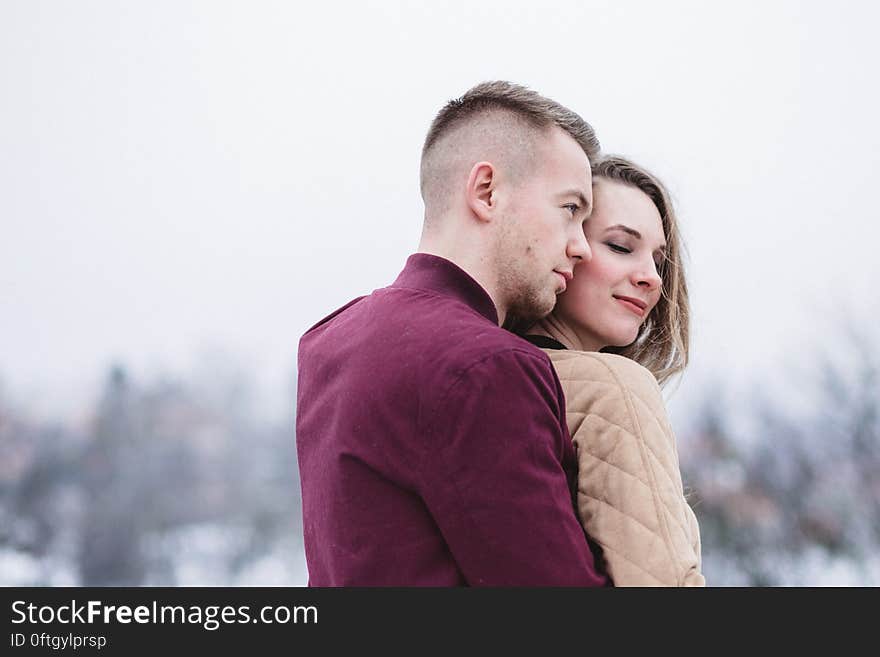 A man hugging a woman from behind outdoors. A man hugging a woman from behind outdoors.