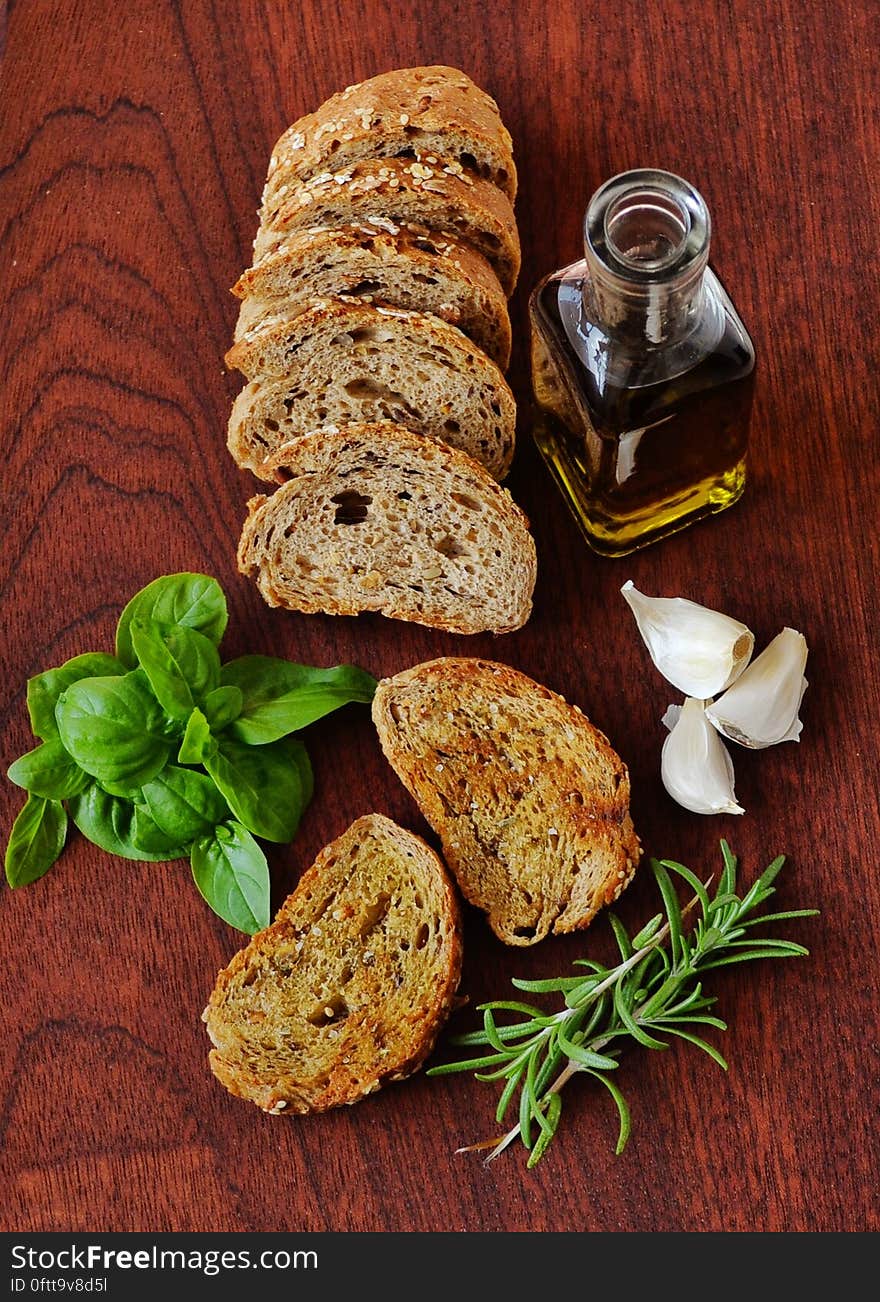 A kitchen counter with slices of bread, olive oil and herbs. A kitchen counter with slices of bread, olive oil and herbs.