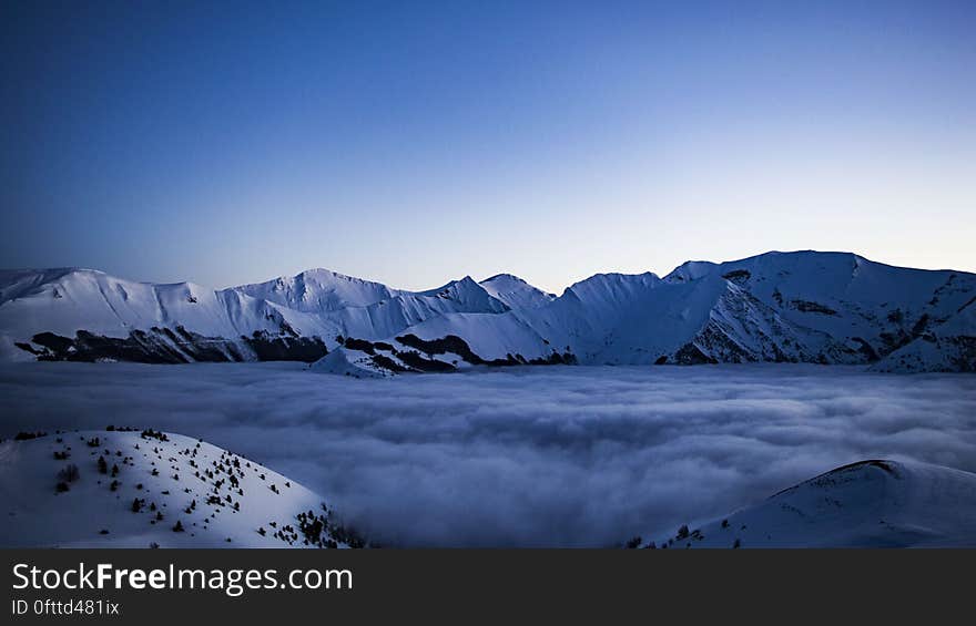 A mountain valley in fog and snowcapped peaks in the background.