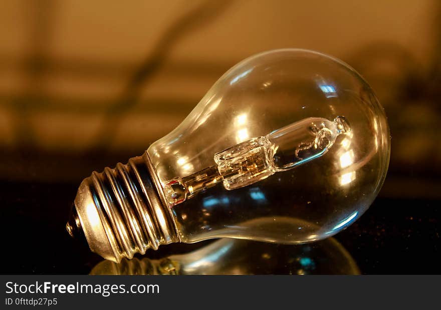 Close up of clear incandescent glass light bulb on table. Close up of clear incandescent glass light bulb on table.