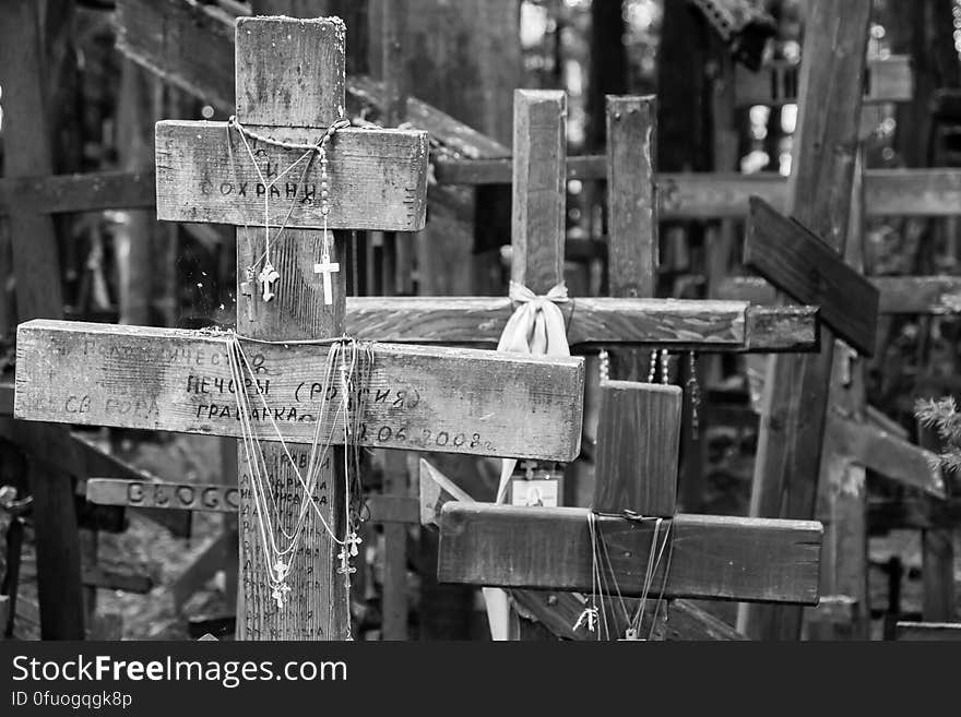 Crosses on chains hanging from rustic wooden crosses in black and white.