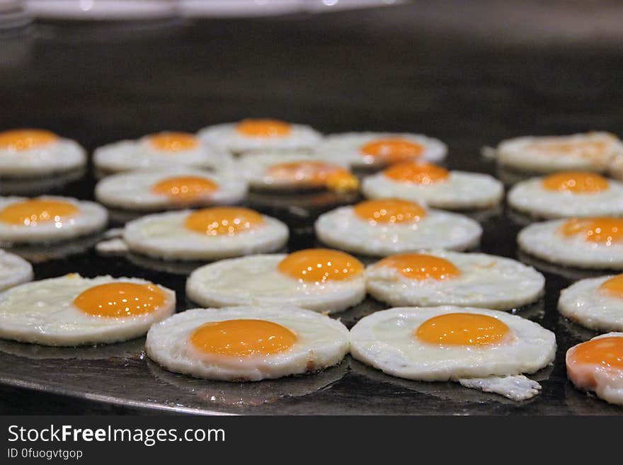 Close up of sunny side up fried eggs on griddle.