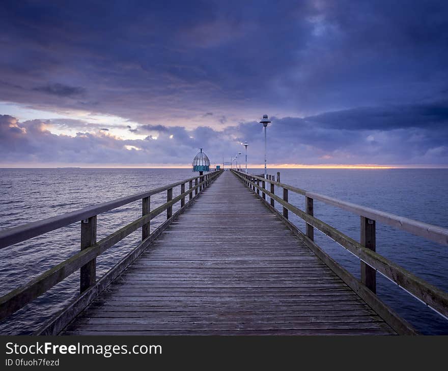 A wooden pier leading to the sea with dark clouds above. A wooden pier leading to the sea with dark clouds above.