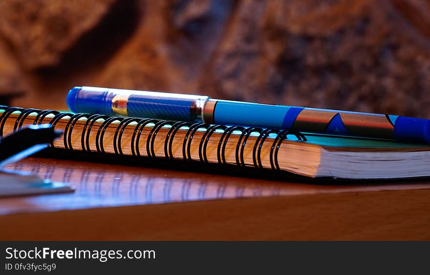 Close up of pen on spiral notebook on wooden table. Close up of pen on spiral notebook on wooden table.