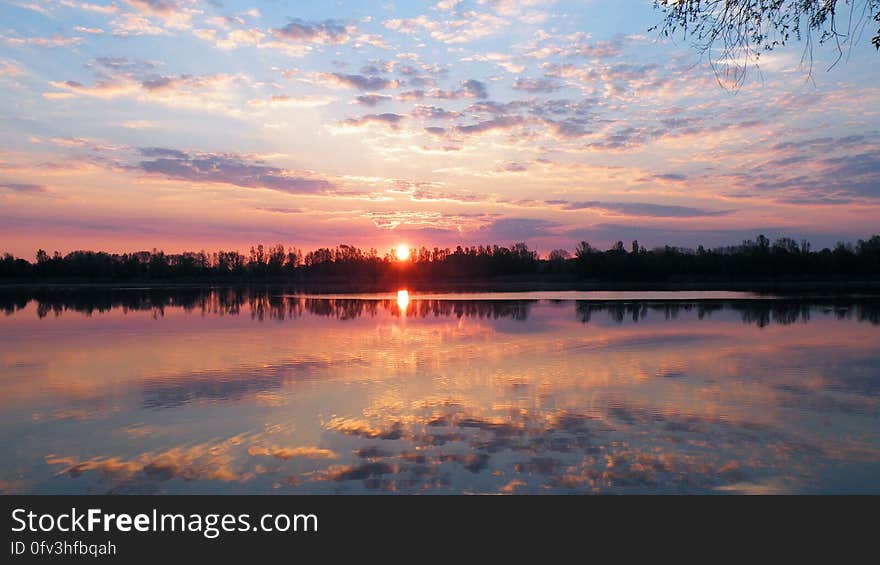 Sun set in horizon reflecting in calm waters with cloudy skies. Sun set in horizon reflecting in calm waters with cloudy skies.