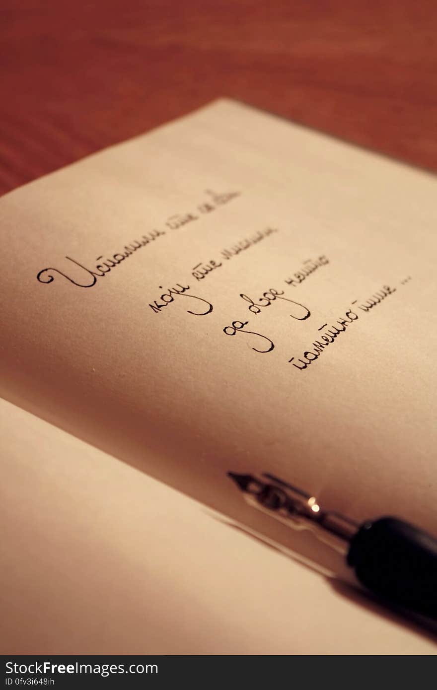 Close up of handwritten text in black ink on parchment pages in book on table. Close up of handwritten text in black ink on parchment pages in book on table.