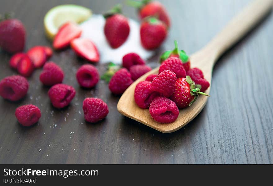 Close up of fresh ripe whole organic red raspberries on wooden spoon resting on wooden table. Close up of fresh ripe whole organic red raspberries on wooden spoon resting on wooden table.