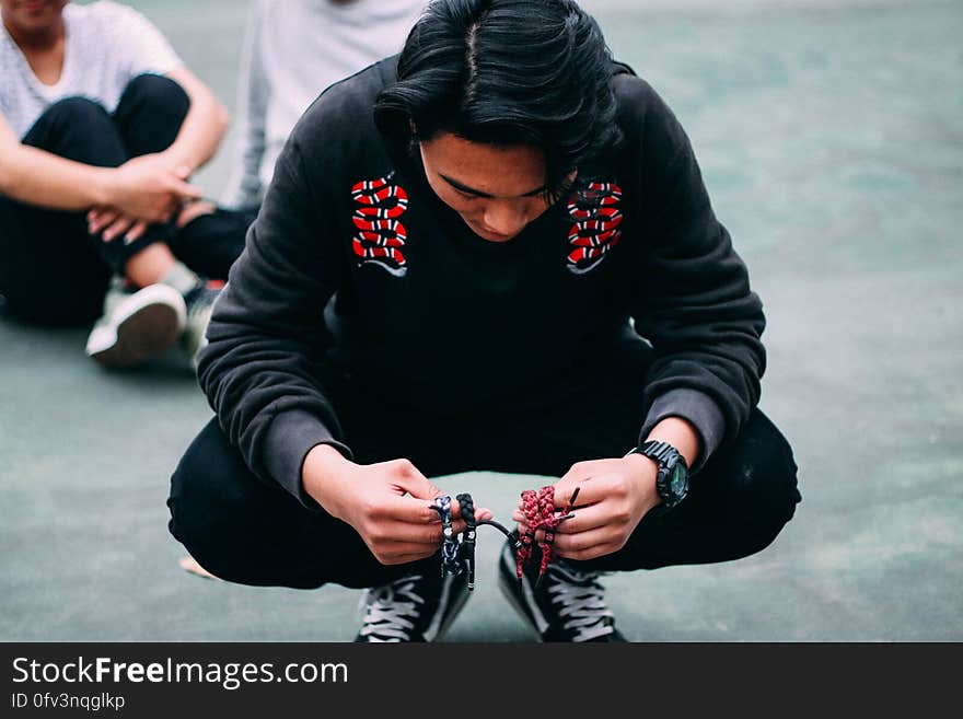 Portrait of man wearing black pants and shirt squatting outdoors on streets. Portrait of man wearing black pants and shirt squatting outdoors on streets.