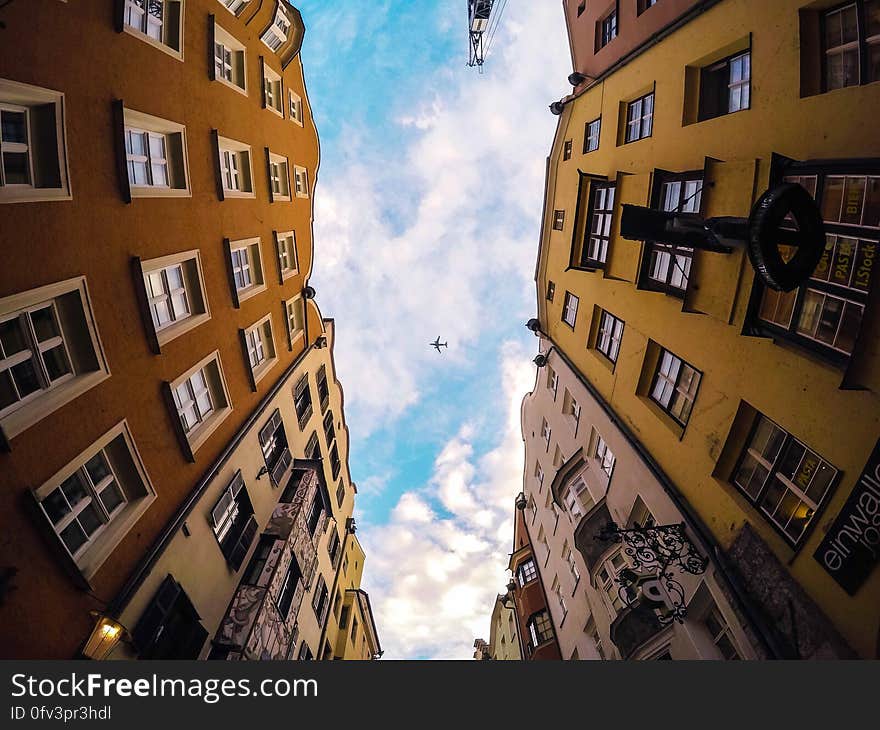 Airplane flying high over facade of modern townhouse buildings on sunny day in blue skies. Airplane flying high over facade of modern townhouse buildings on sunny day in blue skies.