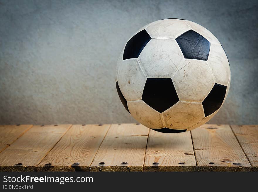 Black and white soccer ball hovering over rustic wooden boards with copy space. Black and white soccer ball hovering over rustic wooden boards with copy space.