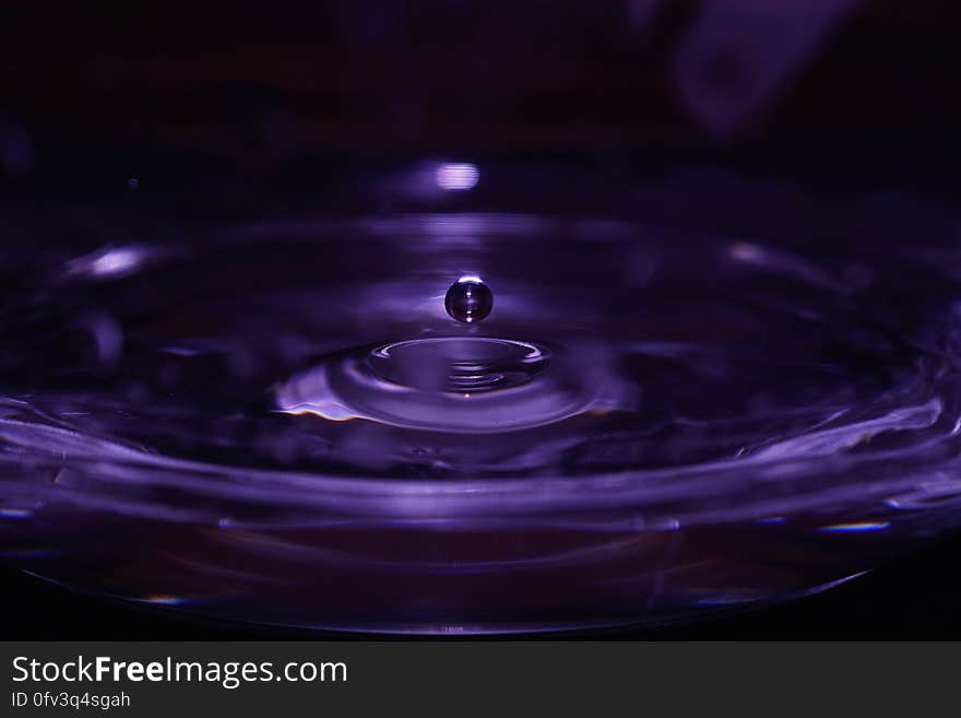 Water drop splashing with ripples in purple liquid. Water drop splashing with ripples in purple liquid.