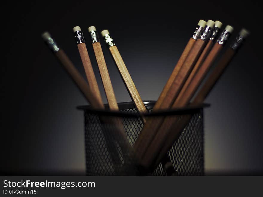 A close up of wooden pencils in a black metal pencil holder. A close up of wooden pencils in a black metal pencil holder.