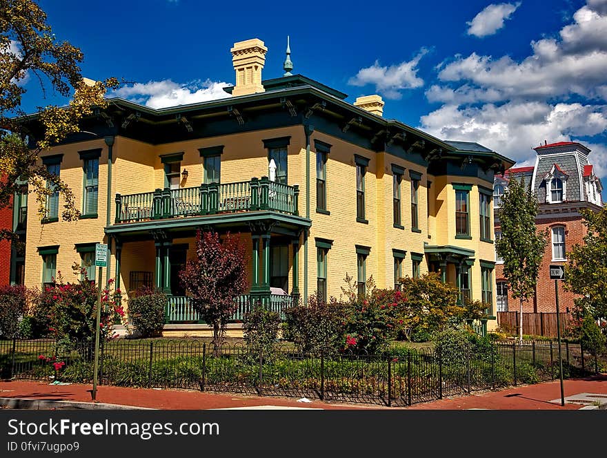 Exterior of mansions with balconies with fenced gardens against blue skies on sunny day. Exterior of mansions with balconies with fenced gardens against blue skies on sunny day.