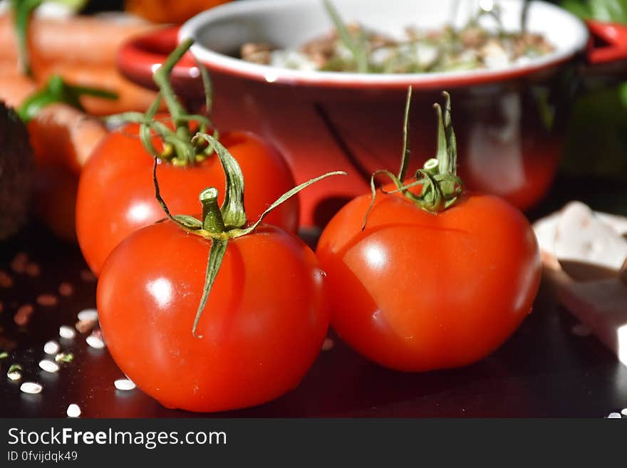 A table with food and three red tomatoes.