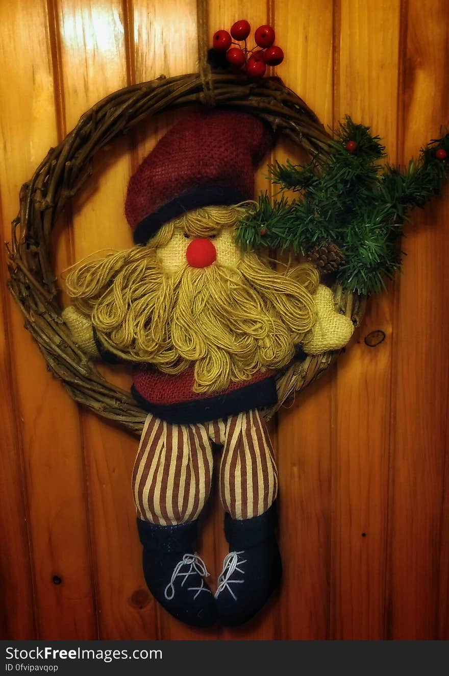 Christmas wreath with pine bow and cloth Santa Claus hanging on wooden planks. Christmas wreath with pine bow and cloth Santa Claus hanging on wooden planks.