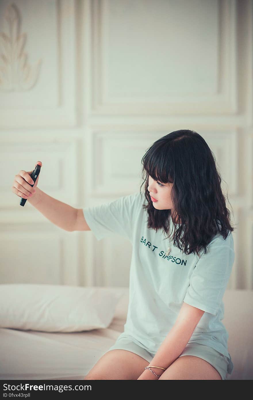 Girl in Blue Crew Neck Shirt Using Her Mobile Phone Indoors