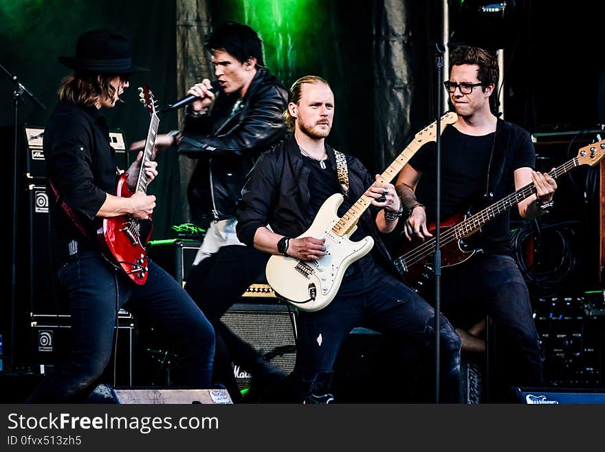 Adult male rock band performing on stage with electric guitars and singer. Adult male rock band performing on stage with electric guitars and singer.