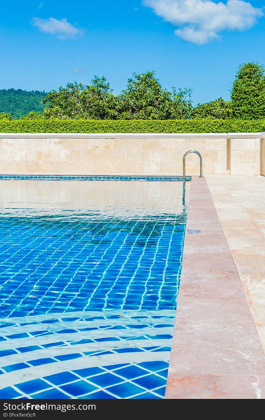 Swimming pool with bright blue tiles outdoors, green countryside and cloudscape background. Swimming pool with bright blue tiles outdoors, green countryside and cloudscape background.