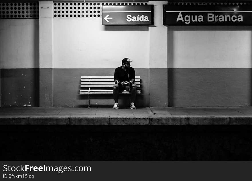 Portrait of man sitting on bench on empty train platform in black and white. Portrait of man sitting on bench on empty train platform in black and white.