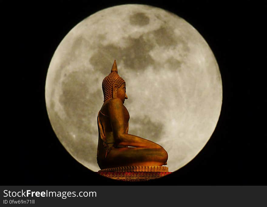 Buddha statue on blurry of full moon background.