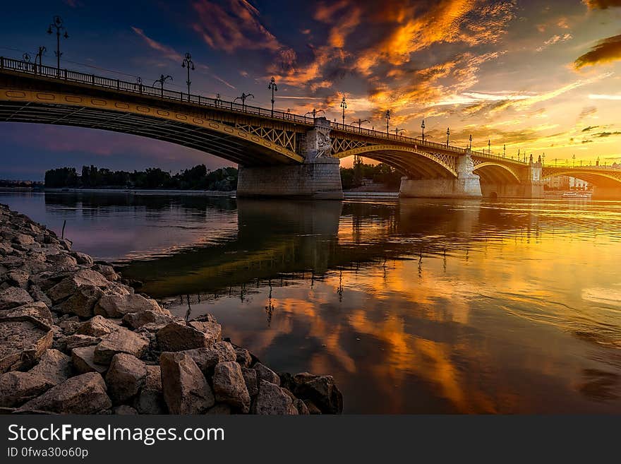 Bridge reflecting in river from rocky banks at sunset. Bridge reflecting in river from rocky banks at sunset.