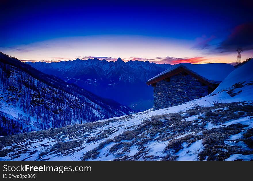 Sunset over alpine cabin on hillside covered in snow, Italy. Sunset over alpine cabin on hillside covered in snow, Italy.