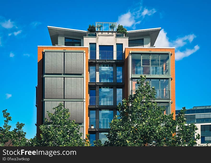 Exterior of modern apartment building with balconies against blue skies on sunny day.