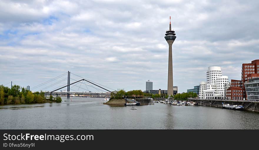 High rise tower and bridge in city skyline along waterfront on sunny day.