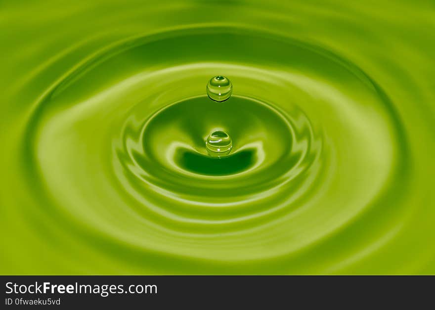 Water drop with ripples on green.