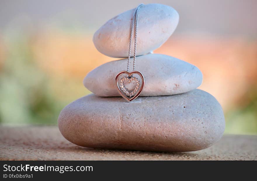 Close up of meditation stones stacked with silver and diamond heart pendant on chain with bokeh background. Close up of meditation stones stacked with silver and diamond heart pendant on chain with bokeh background.