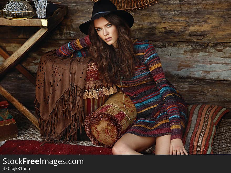 A woman wearing colorful knitted dress sitting on pillow. A woman wearing colorful knitted dress sitting on pillow.