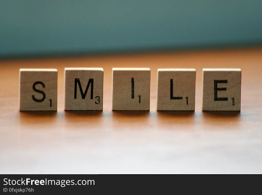 Smile spelled in wooden Scrabble tiles on wooden table. Smile spelled in wooden Scrabble tiles on wooden table.