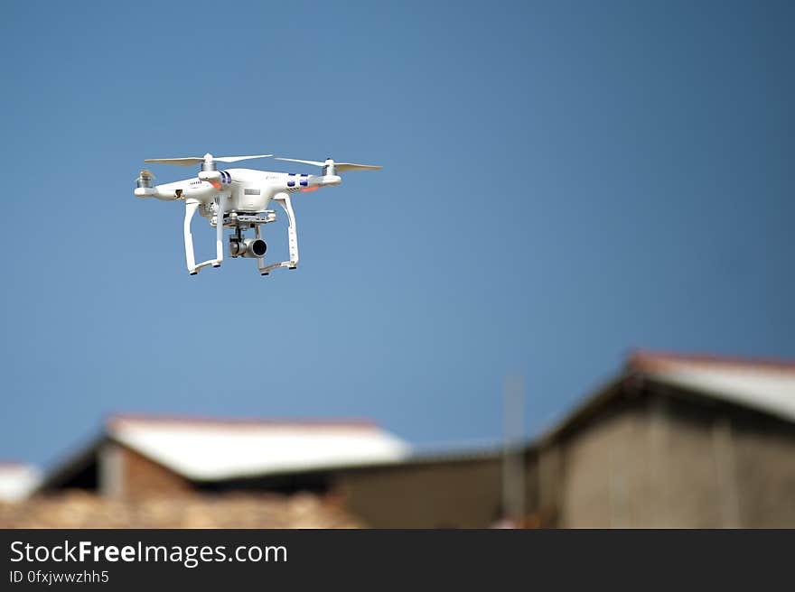 A quadcopter on the sky with houses in the background. A quadcopter on the sky with houses in the background.