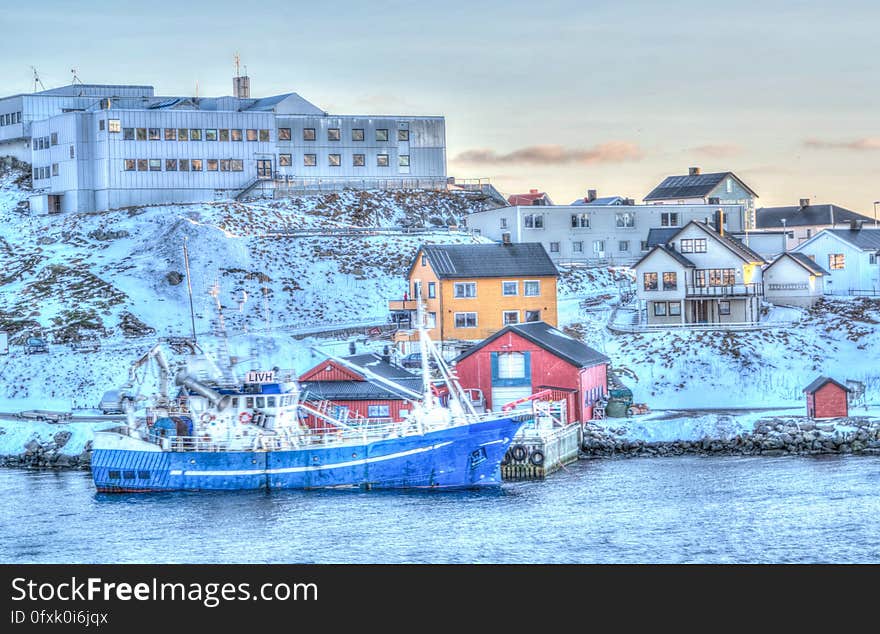 Boat docked on waterfront with colorful houses covered in snow. Boat docked on waterfront with colorful houses covered in snow.