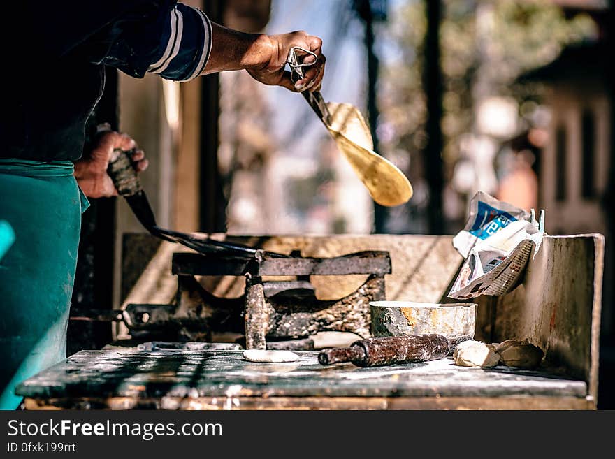 Man cooking naan on open fire outdoors.