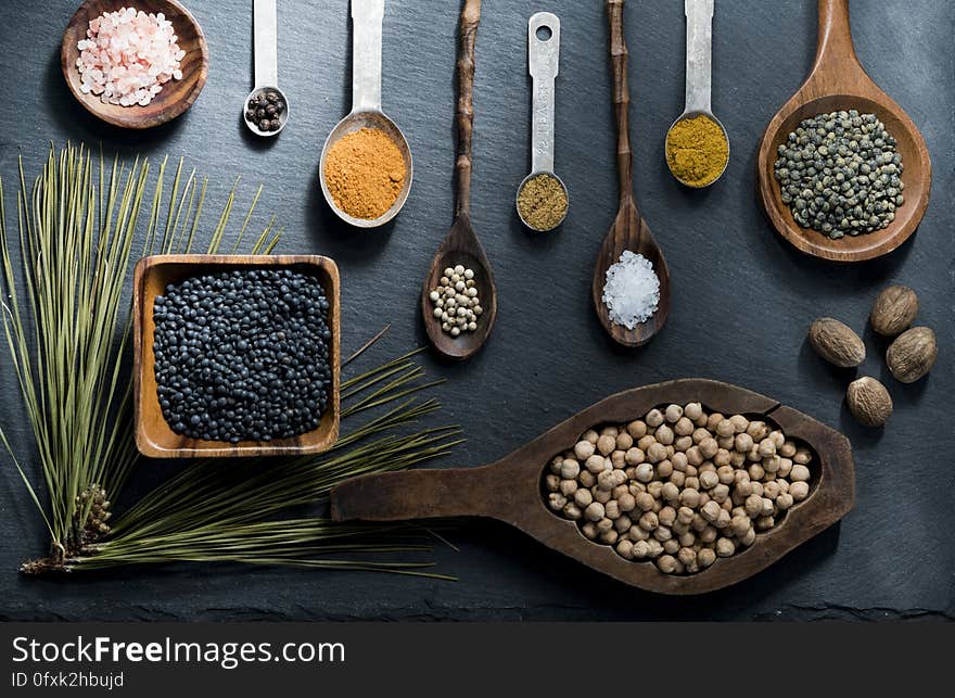 Lay flat overhead of spices in various wooden bowls and spoons on slate. Lay flat overhead of spices in various wooden bowls and spoons on slate.