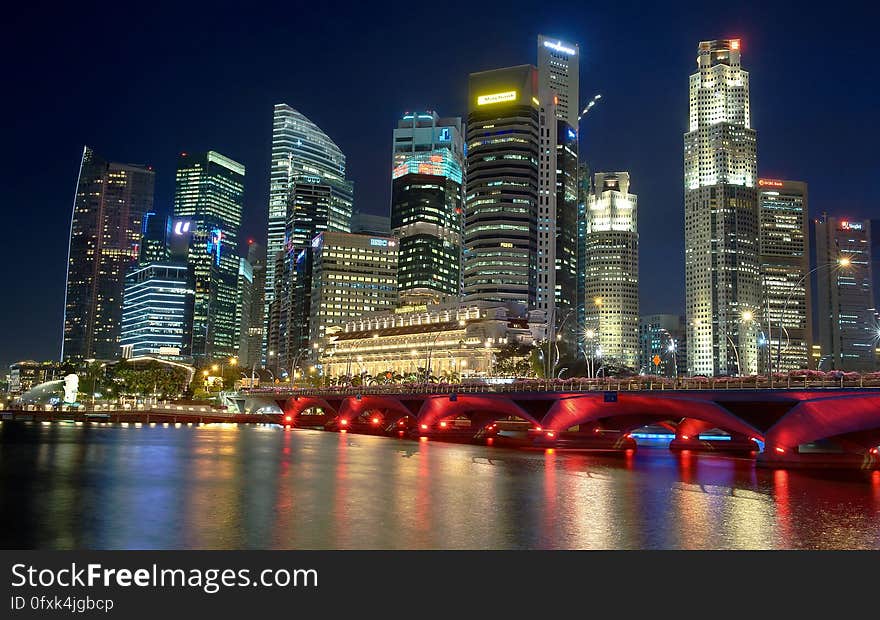 City waterfront with a red lit arched bridge at night. City waterfront with a red lit arched bridge at night.