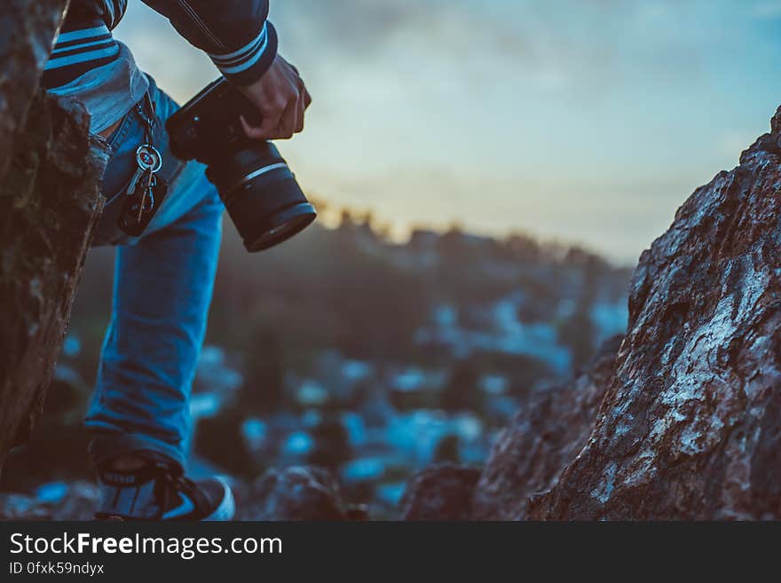 A person with a DSLR camera on the top of a mountain. A person with a DSLR camera on the top of a mountain.