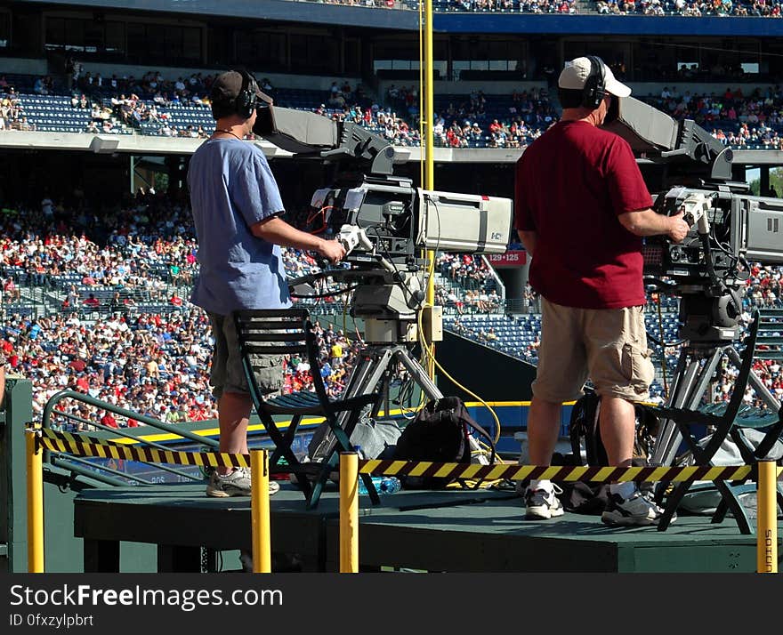 2 Camera Man Standing in a Green Metal Stage during Daytime