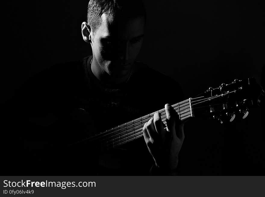 A man playing the guitar in the dark. A man playing the guitar in the dark.