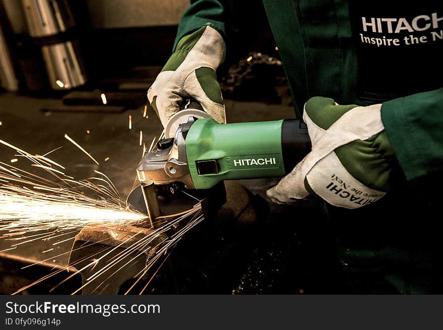 Close up of hands holding mechanical grinder on metal producing sparks inside machine shop. Close up of hands holding mechanical grinder on metal producing sparks inside machine shop.