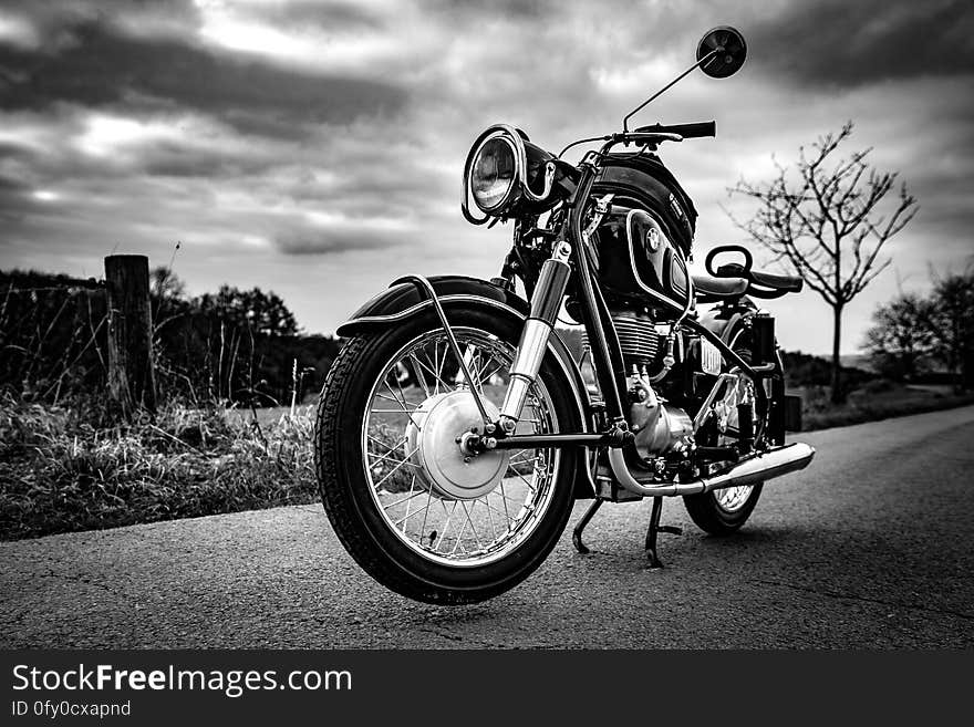 A black and white photo of a motorbike on a road. A black and white photo of a motorbike on a road.