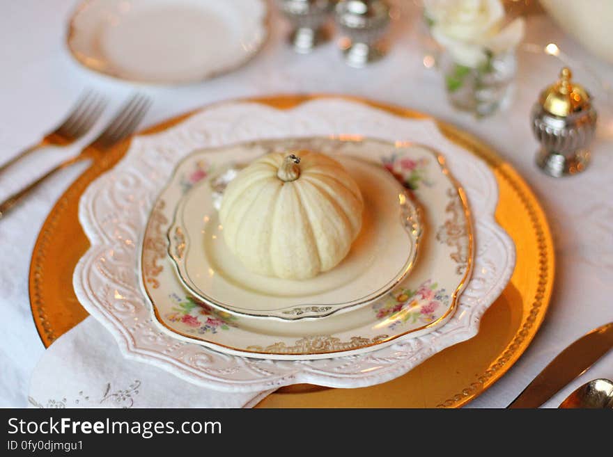 A table set with plates and utensils and a pumpkin on the plate. A table set with plates and utensils and a pumpkin on the plate.