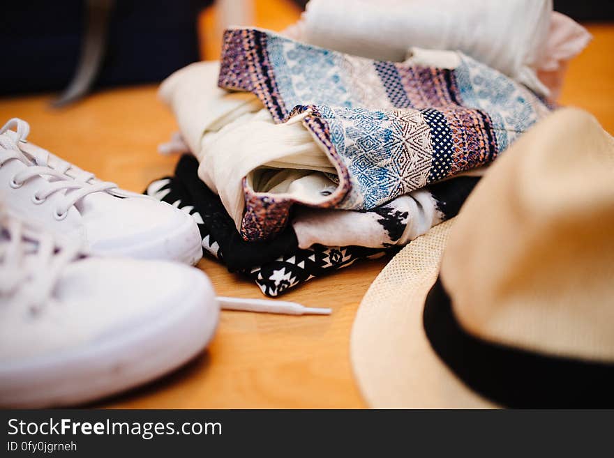 Brown Fedora Hat Beside White Sneakers and Blue Textile