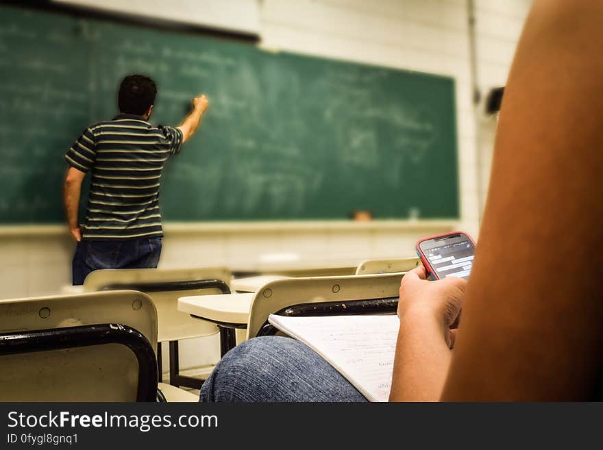 Man in Black and White Polo Shirt Beside Writing Board